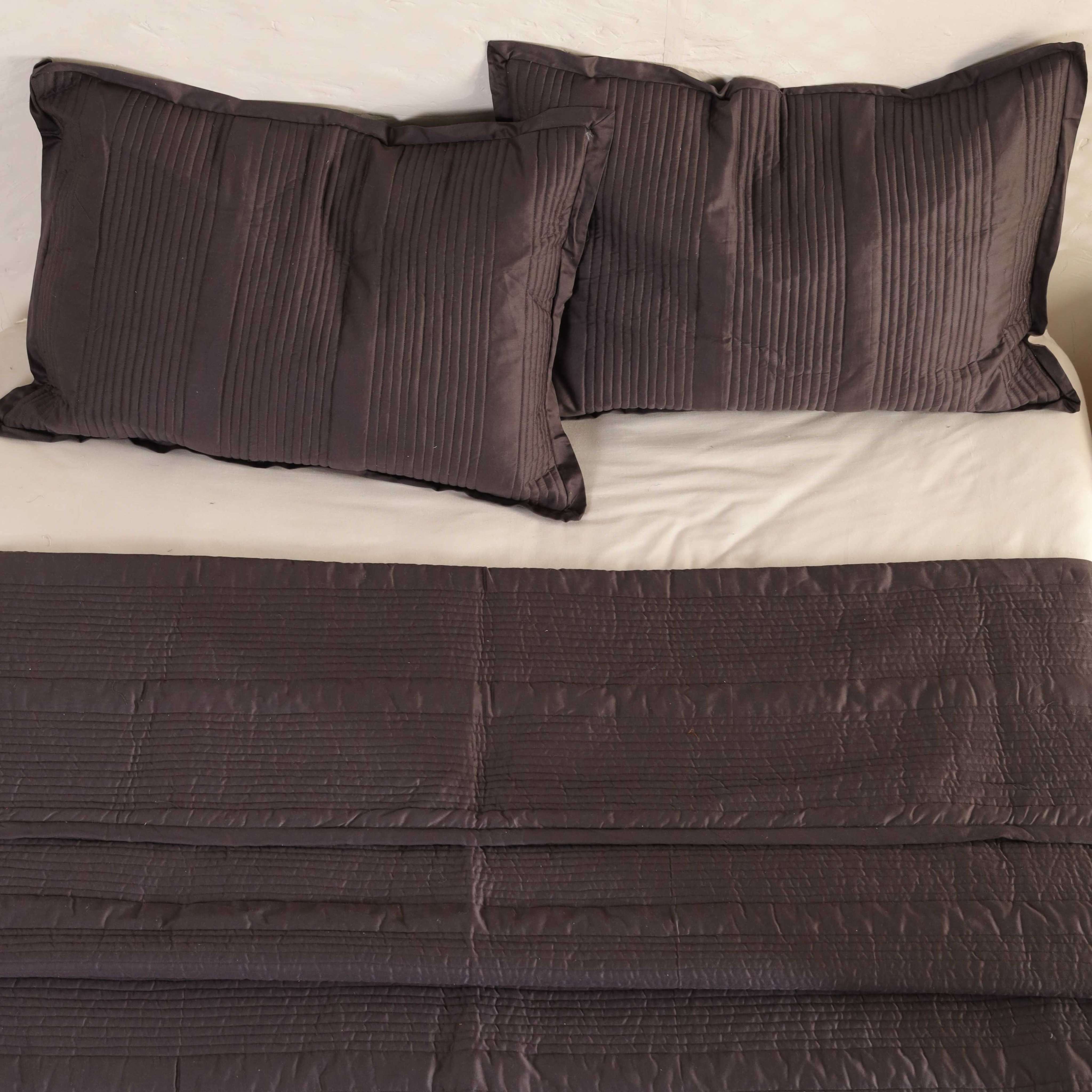 Modern bedroom interior featuring a deep brown velvet quilt and neutral accents.