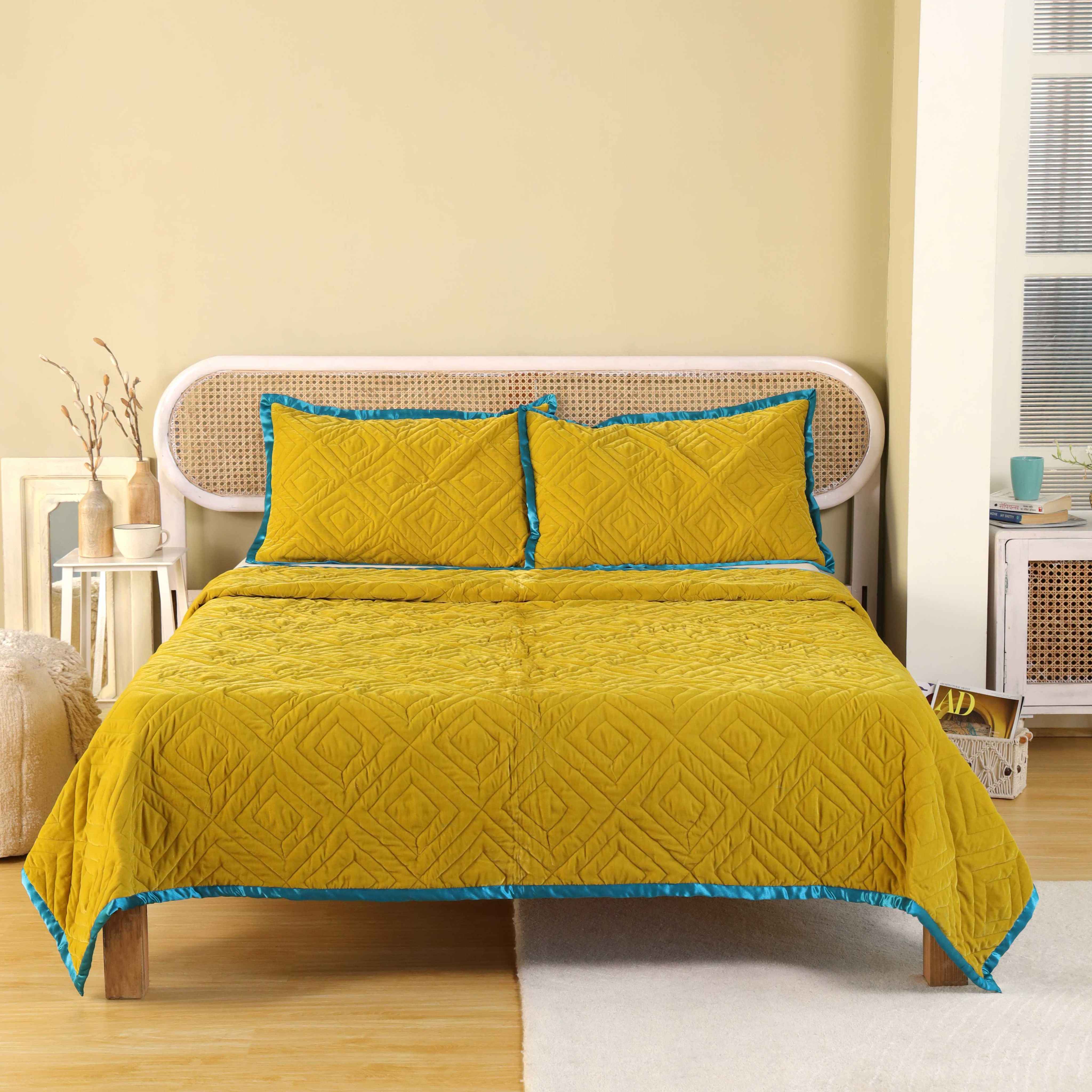 Mustard yellow satin duvet cover with intricate diamond quilting and a vibrant teal blue border.