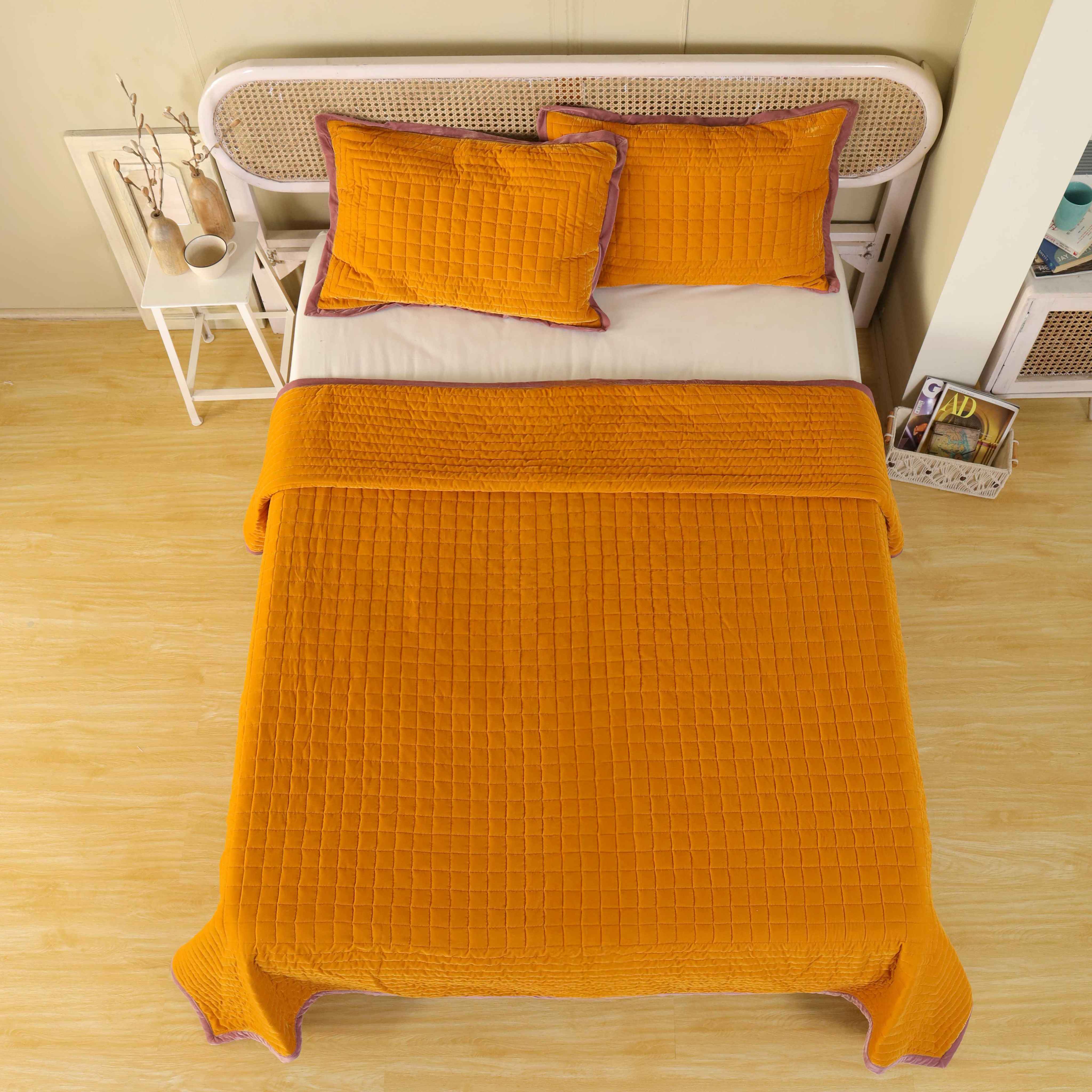 Mustard yellow velvet duvet cover with mauve trim and square box-stitch quilting on a modern bed.