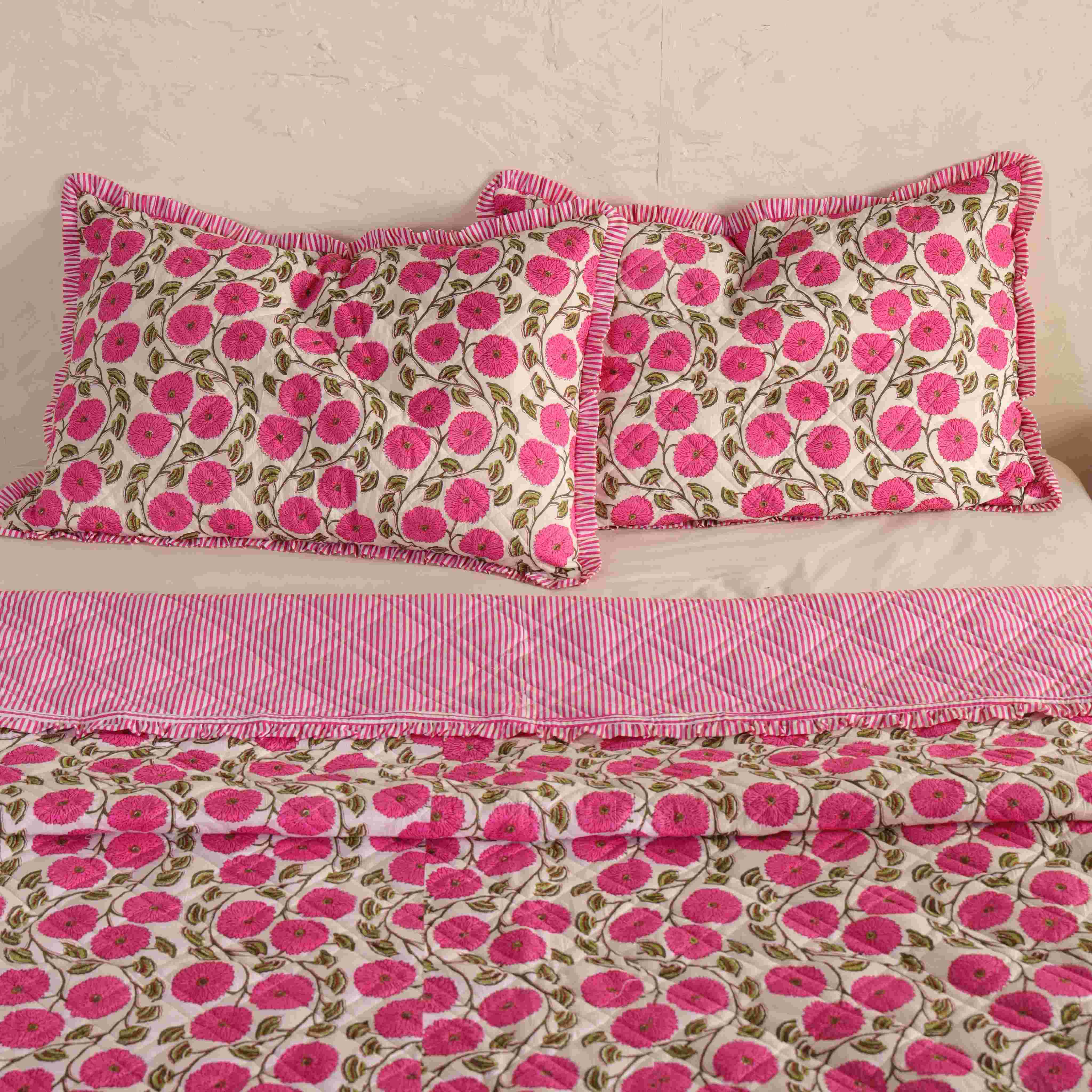 Neatly folded pink floral quilt set showing the lightweight and soft cotton material.
