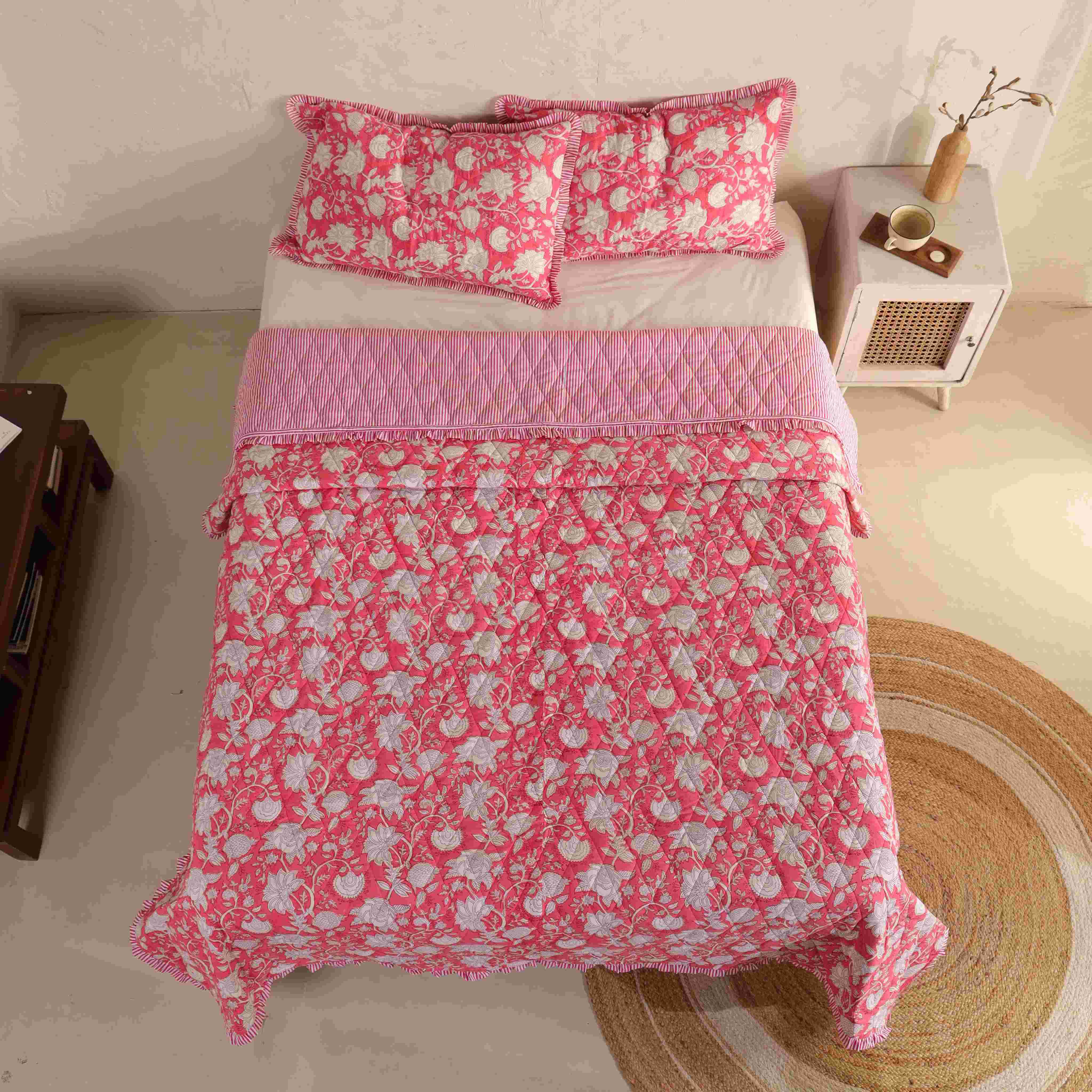 Close-up of the white floral block-print pattern on a rose pink cotton quilt.