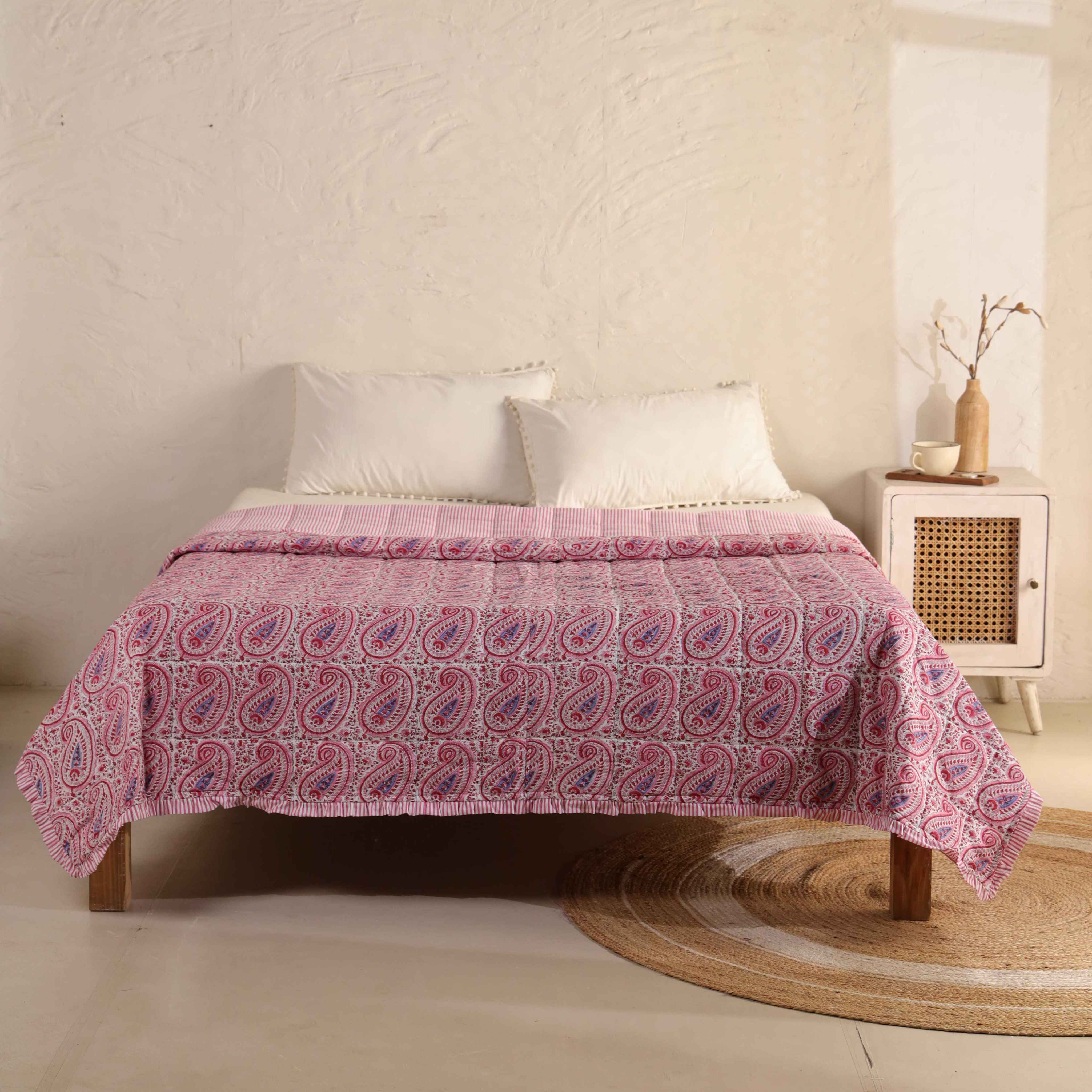 3-piece pink floral cotton quilt set with striped ruffle edges on a bed.