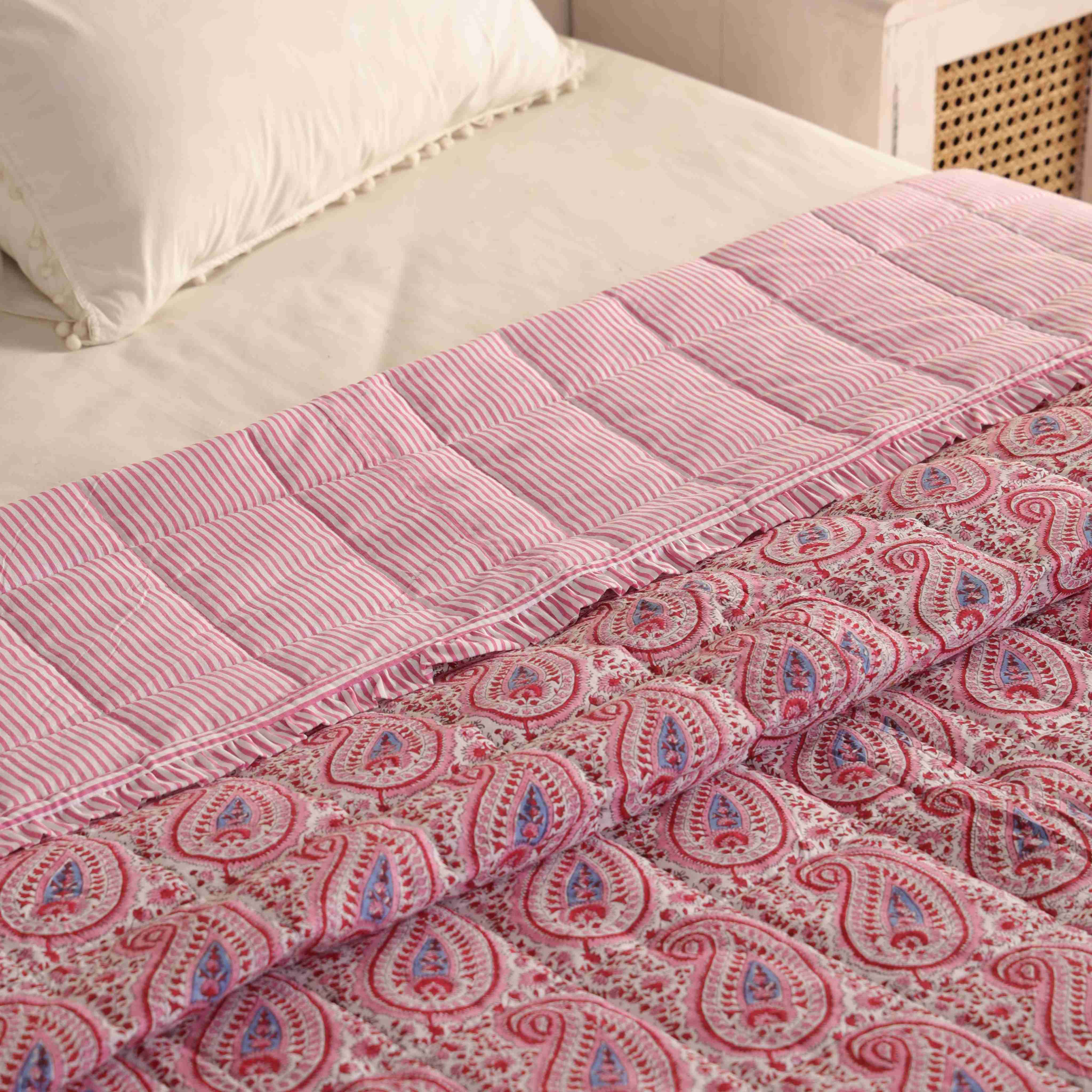 Pink and white paisley cotton quilt set styled in a bright, modern bedroom.