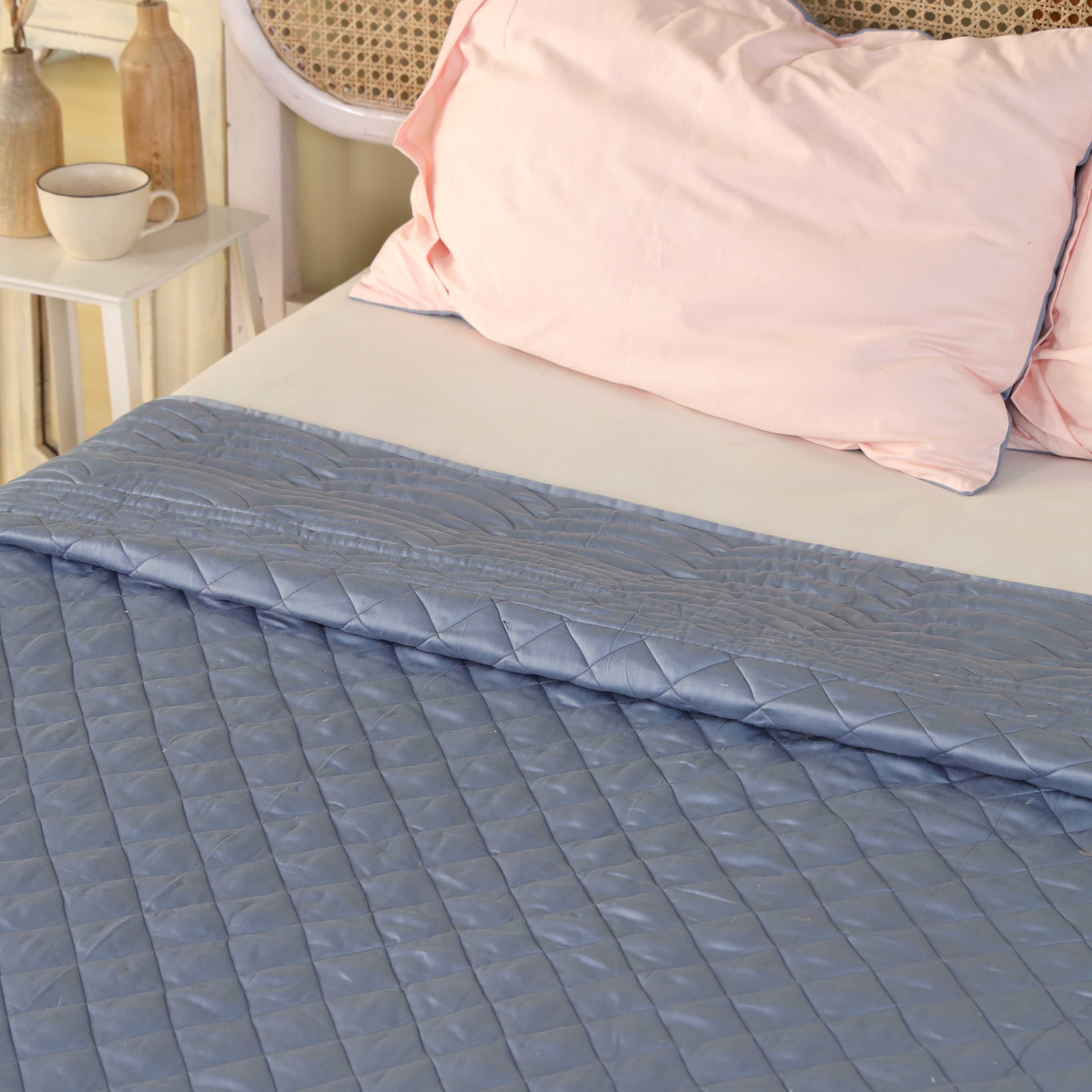 Two solid blush pink silky satin pillow covers on a bed.