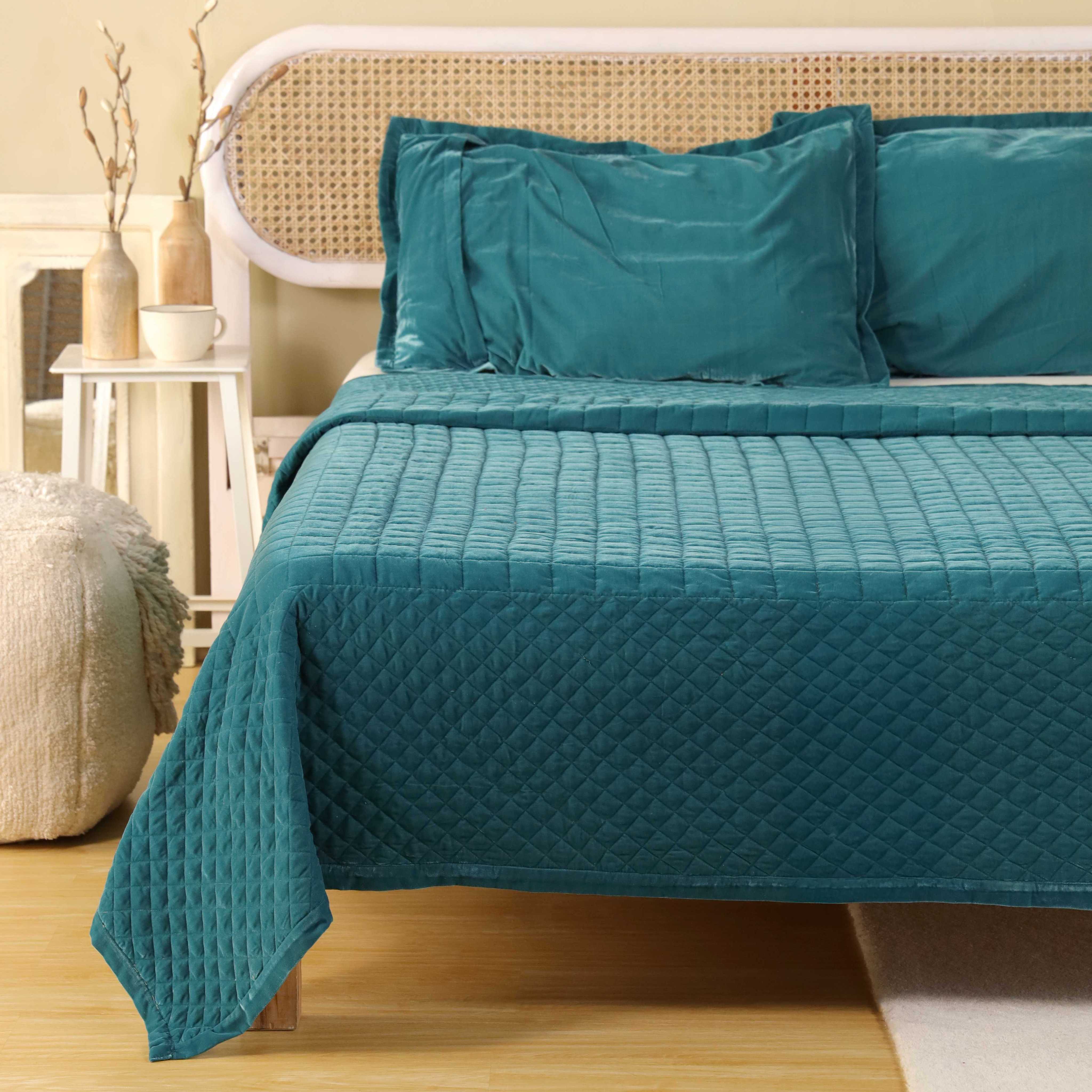 Matching teal blue velvet pillow covers with high-quality quilted stitching details.