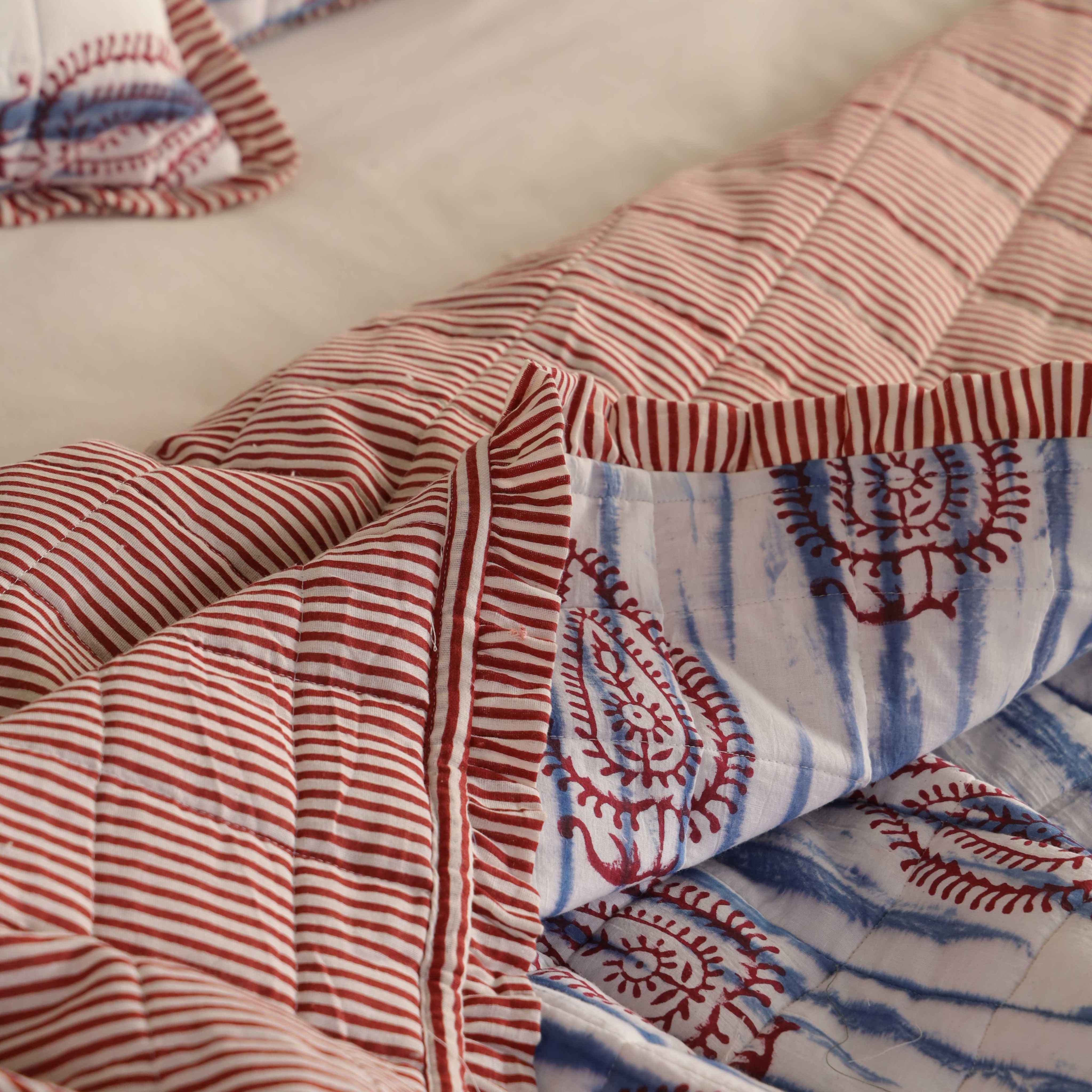 Two matching blue and white cotton pillow covers with red striped ruffle borders.