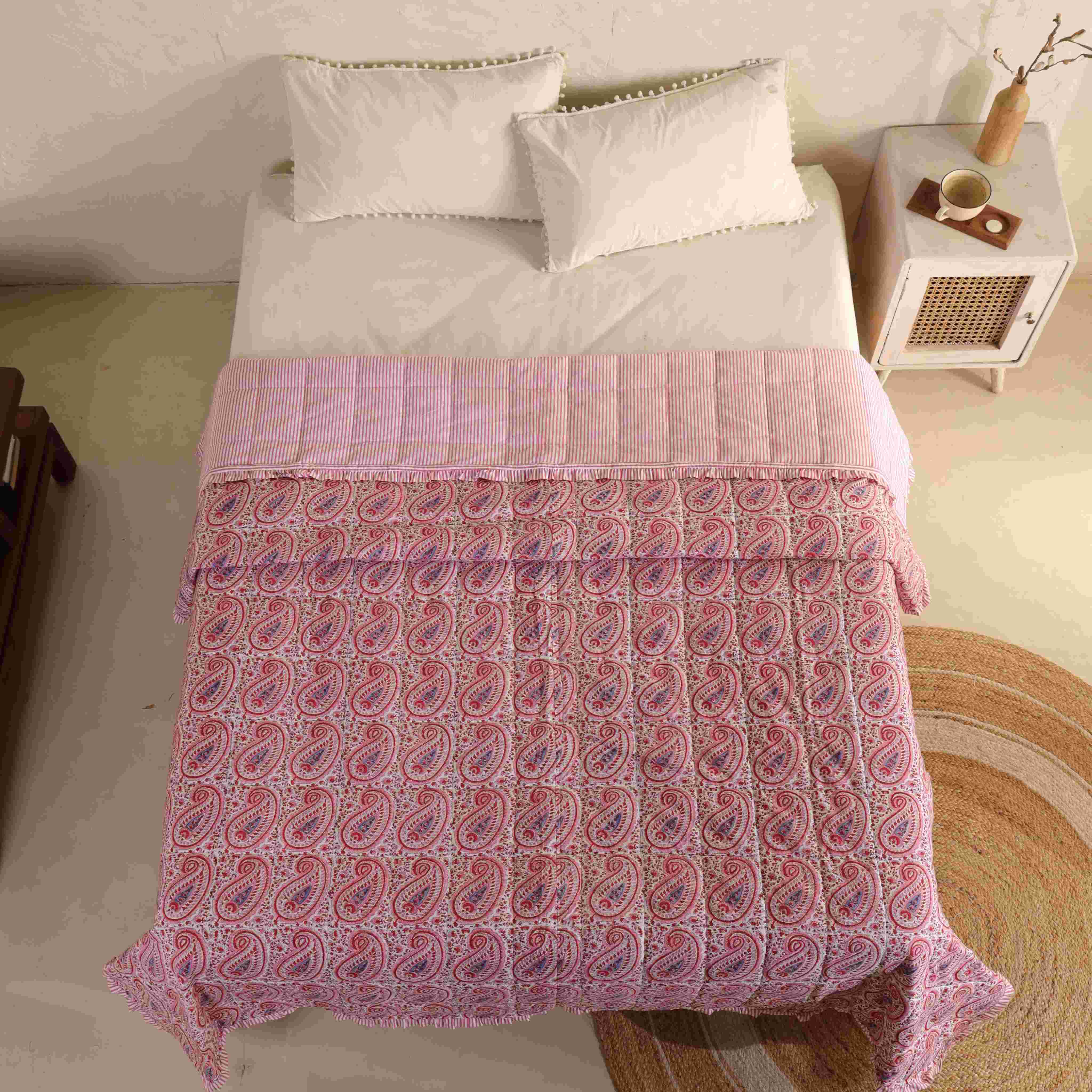 Two matching pink floral cotton pillow covers with striped ruffle accents.