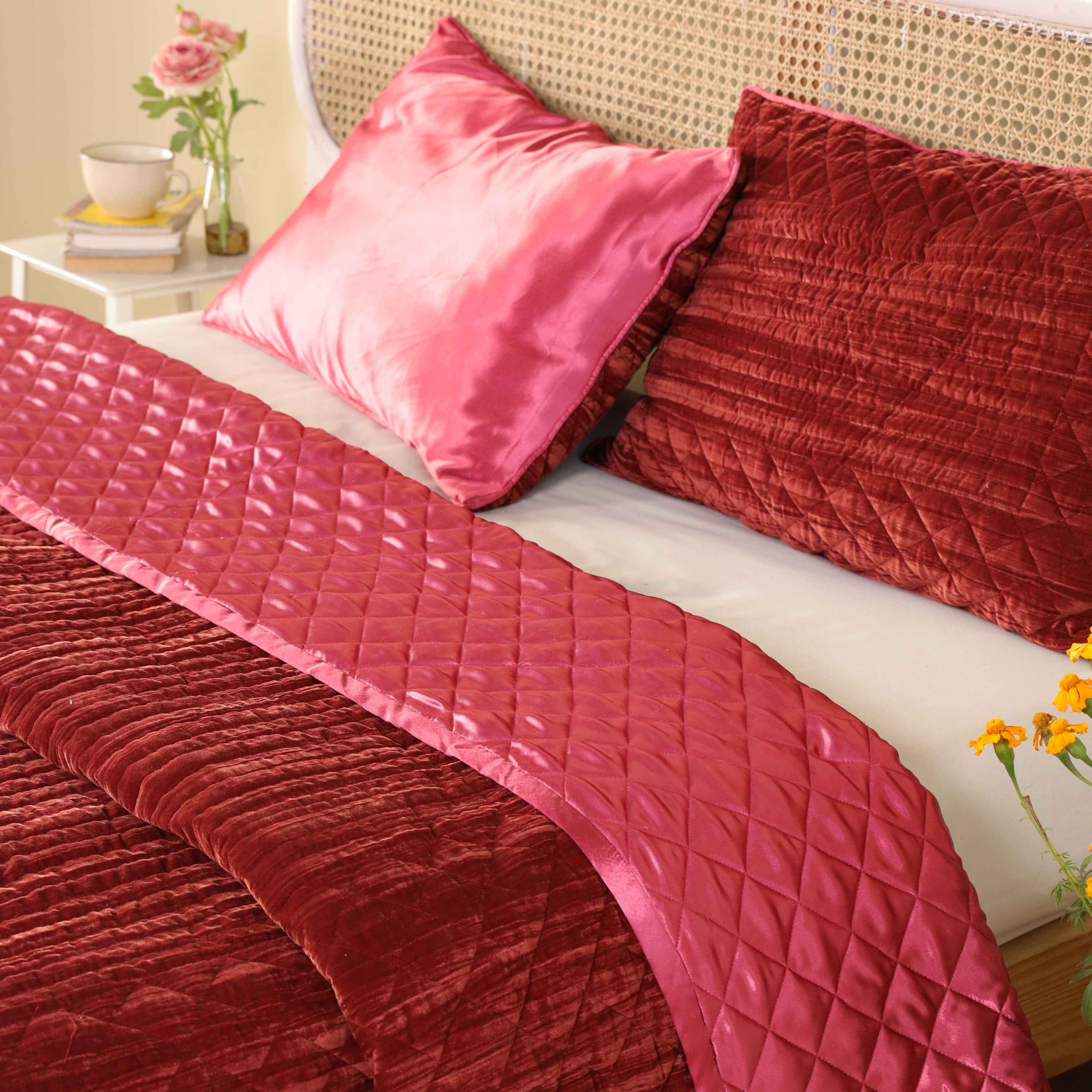 Two matching reversible pillow covers showing the satin and velvet sides in faded maroon