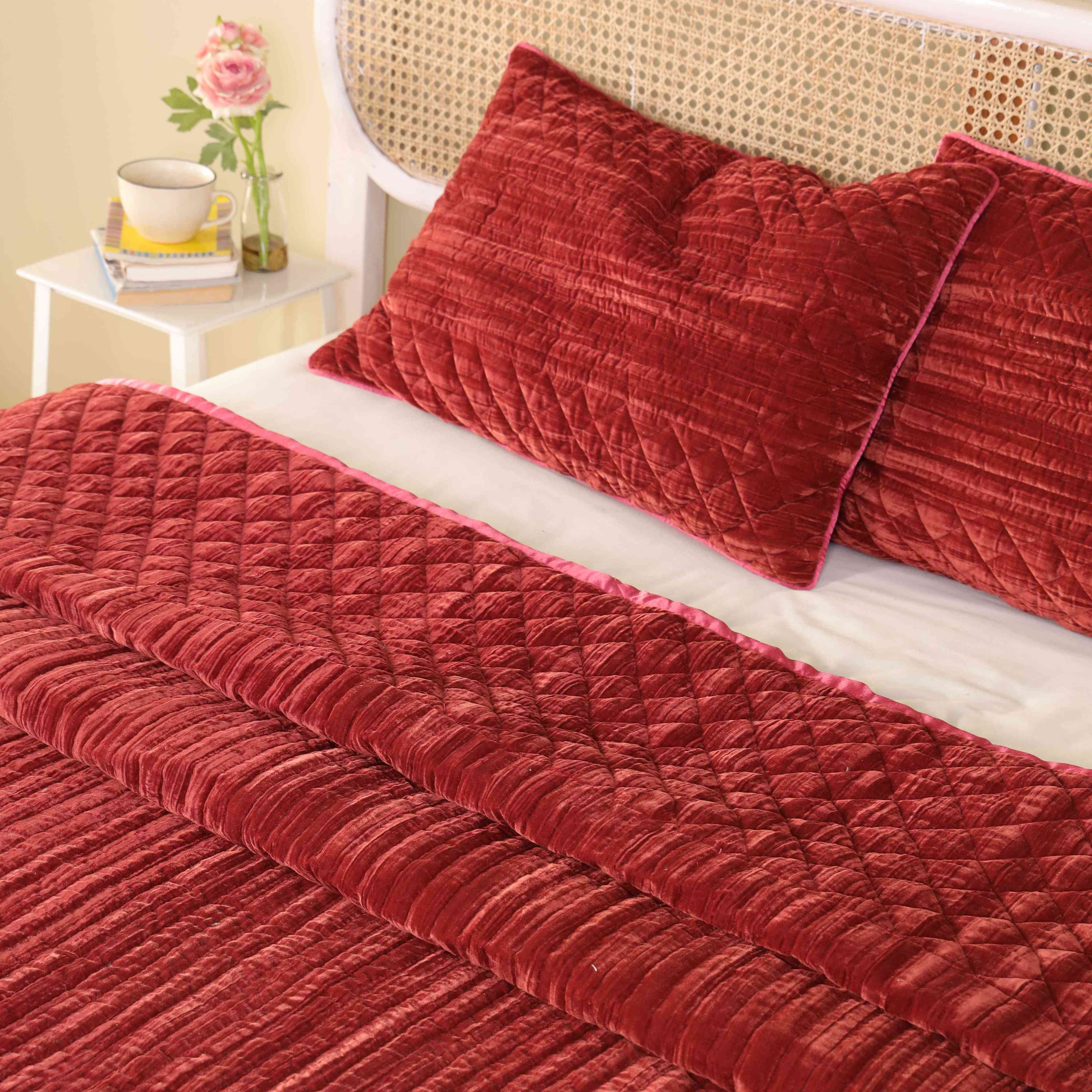 Two matching velvet pillow covers in faded maroon with intricate horizontal quilting.