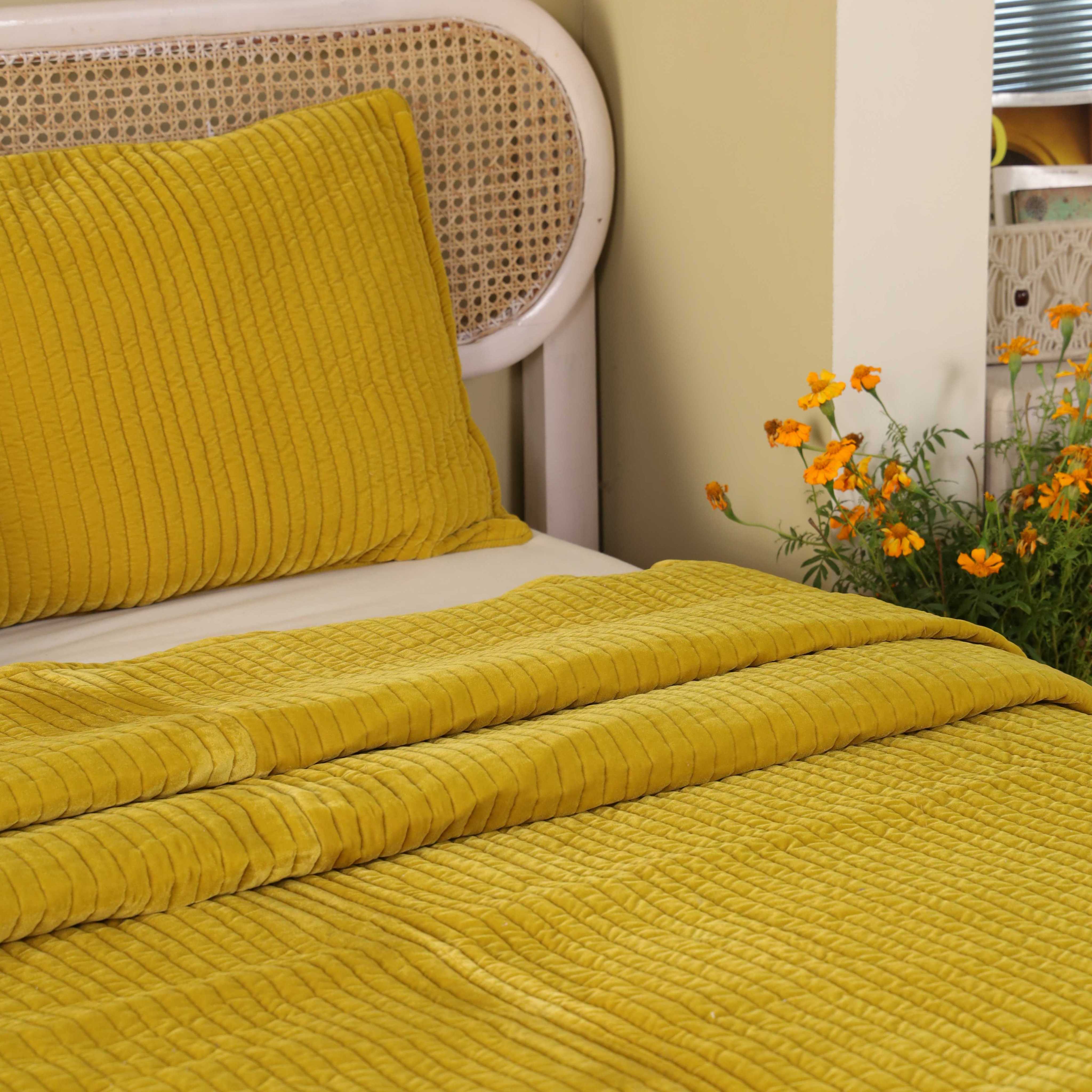 Close-up of the vertical quilted stitching on soft mustard yellow velvet fabric.